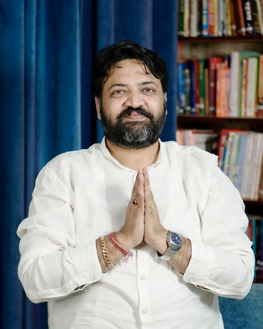 Dr Deepak greeting with folded hands in front of a library